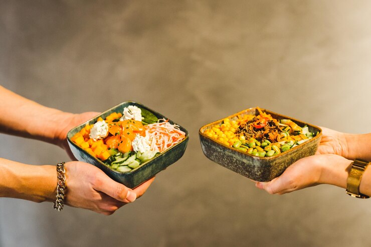 Image of two people holding bowls full of fresh food. Find peace with food and your body with the support of a skilled eating disorder recovery coach in the United Kingdom.