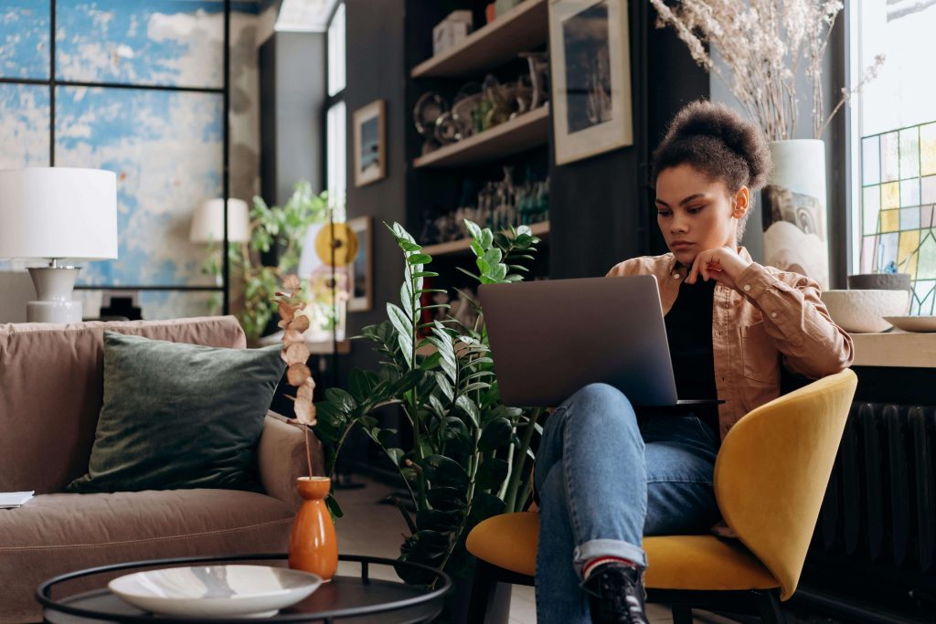 woman holding laptop | eating disorder recovery coaching in the uk | eating disorder recovery coach in the uk | eating disorder coaching | british eating disorder recovery coach | England | Scotland | Ireland Image of a thoughtful African-American woman sitting in a yellow chair with a laptop on her lap. As a busy professional it can be difficult to manage your eating disorder in healthy ways. With the support of an eating disorder recovery coach in the UK you can begin healing with support soon.
