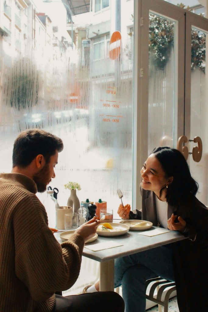 Happy couple sitting at a table eating. Find personalized meal support when it comes to rebuilding trust with food again with eating disorder recovery coaching in the UK.