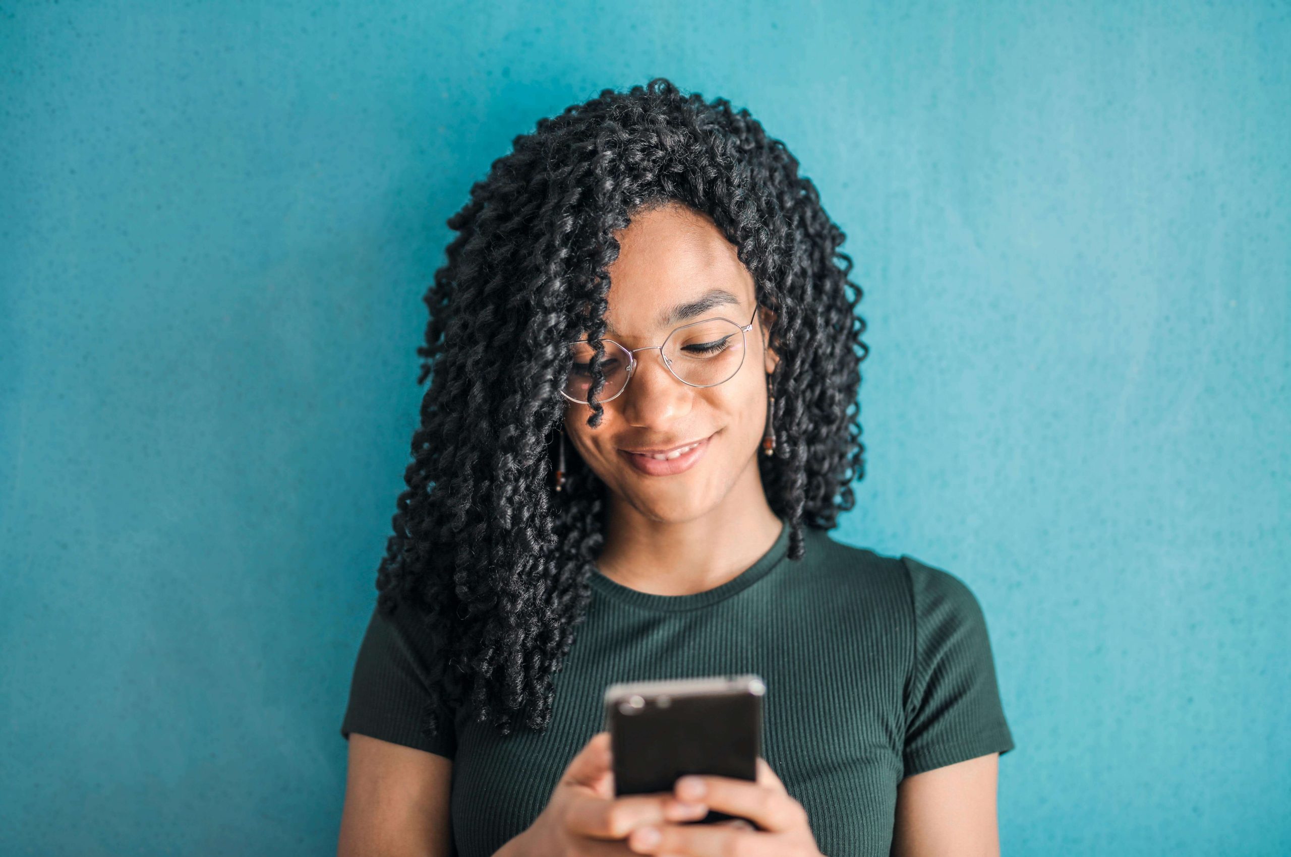 Image of a smiling African American woman texting on her cell phone. With supportive eating disorder recovery coaching in the UK you can begin to build healthy habits to heal from your eating disorder.
