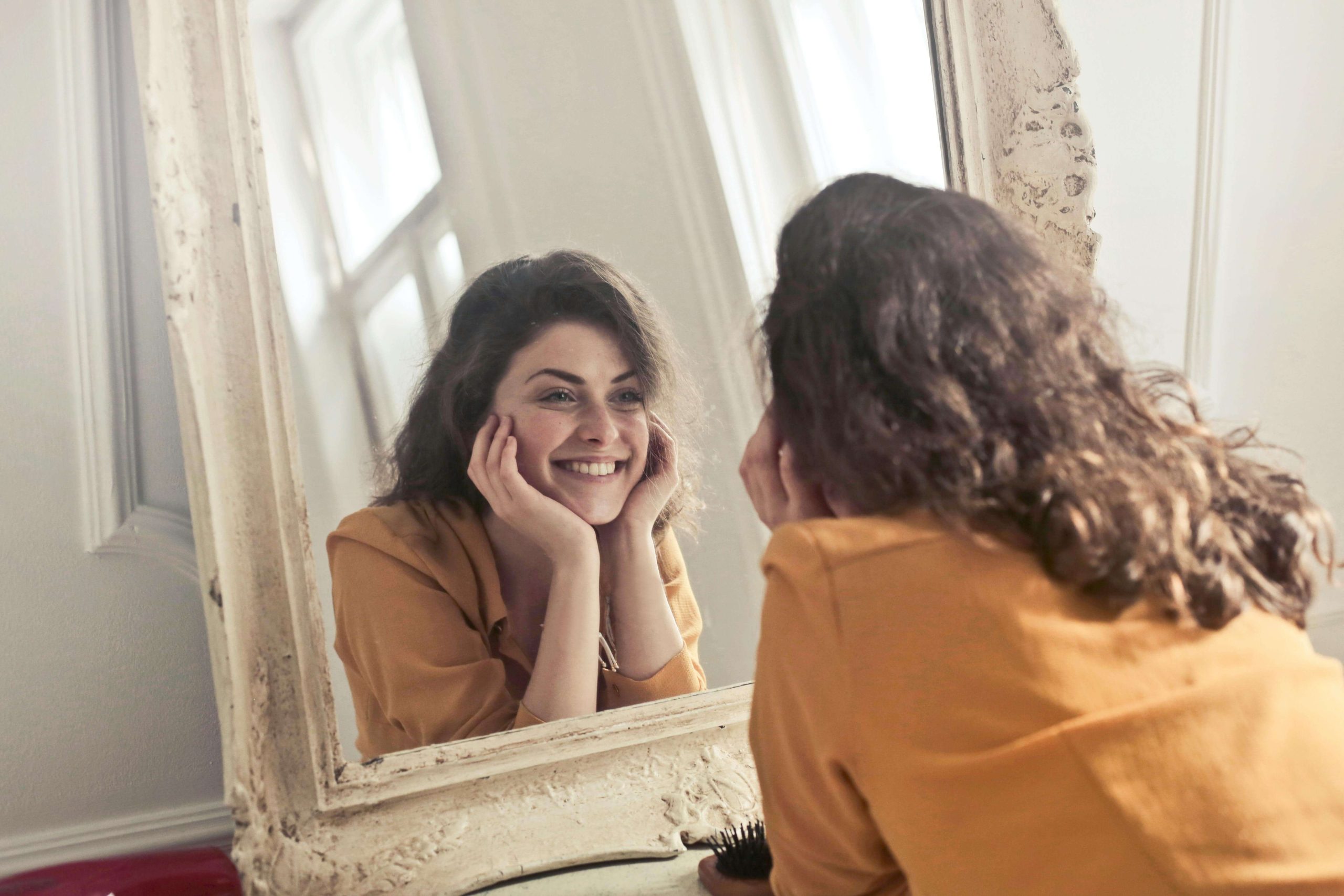 Happy woman laying on the ground smiling into a mirror. With the support of a caring eating disorder recovery coach in the UK you can begin your path to freedom from your eating disorder.