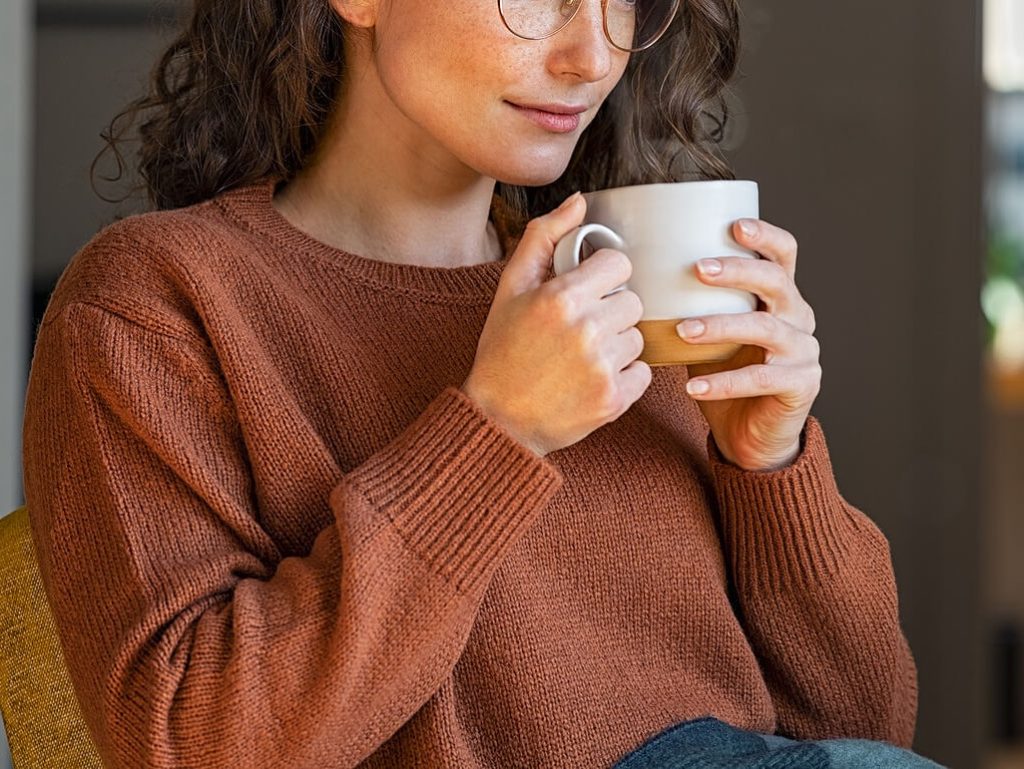 Smiling woman holding a coffee mug. Start making progress in your eating disorder recovery with the support of an eating disorder recovery coach in the UK.