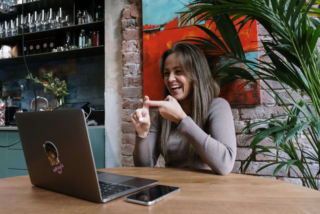 Happy woman talking while on a video call with her laptop in a cafe. With eating disorder recovery coaching in the UK you can begin feeling safe and supported as you challenge your fear foods.