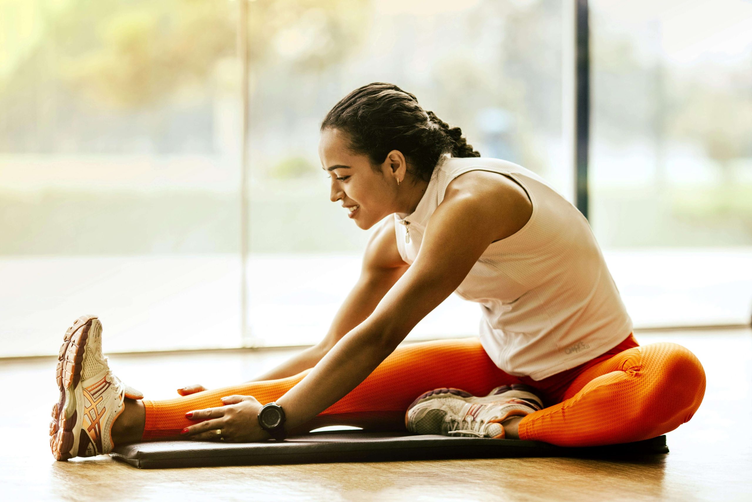 Happy woman athlete sitting on the floor stretching. With eating disorder recovery coaching in the UK you can begin healing from your eating disorder as an athlete in a healthy way.