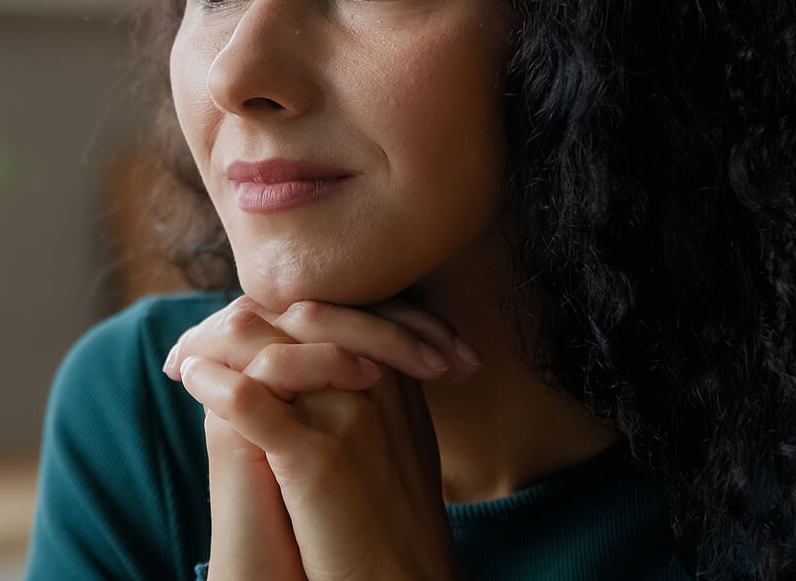 Thoughtful woman resting her chin on her hands. If you're unable to manage your eating disorder alone, find support with eating disorder recovery coaching in the UK to begin healing.