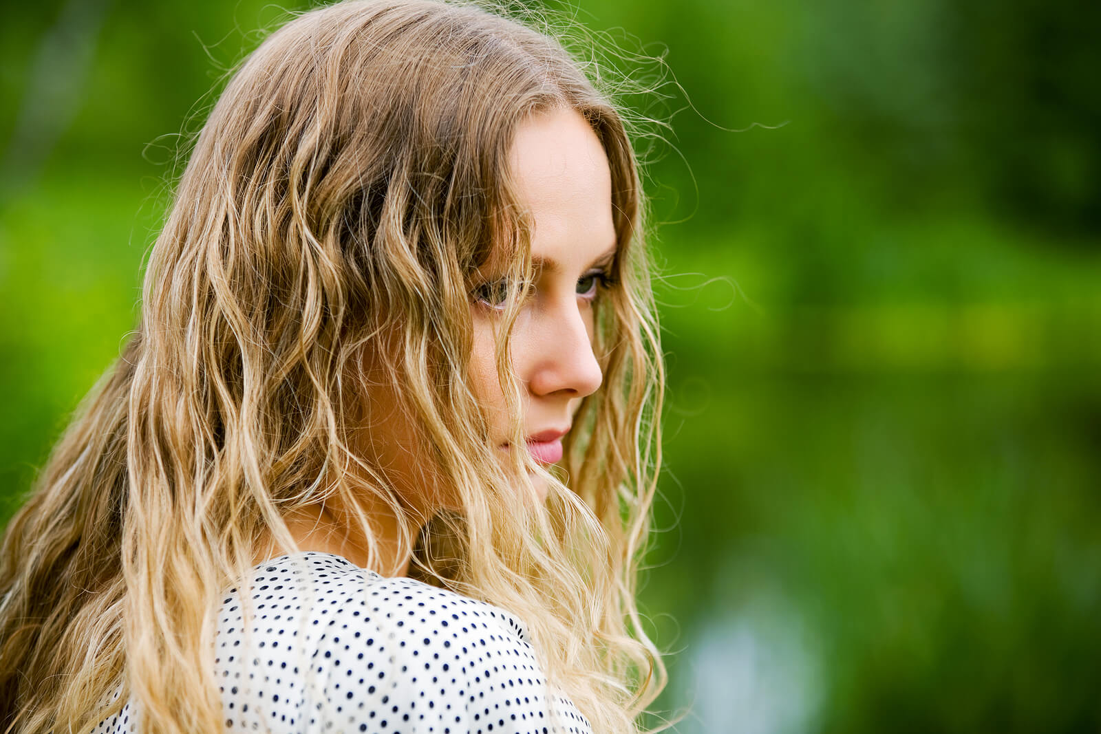 Sad woman standing outside with her hair covering her face. Break free from the rock bottom mindset and begin healing with eating disorder recovery coaching in England.