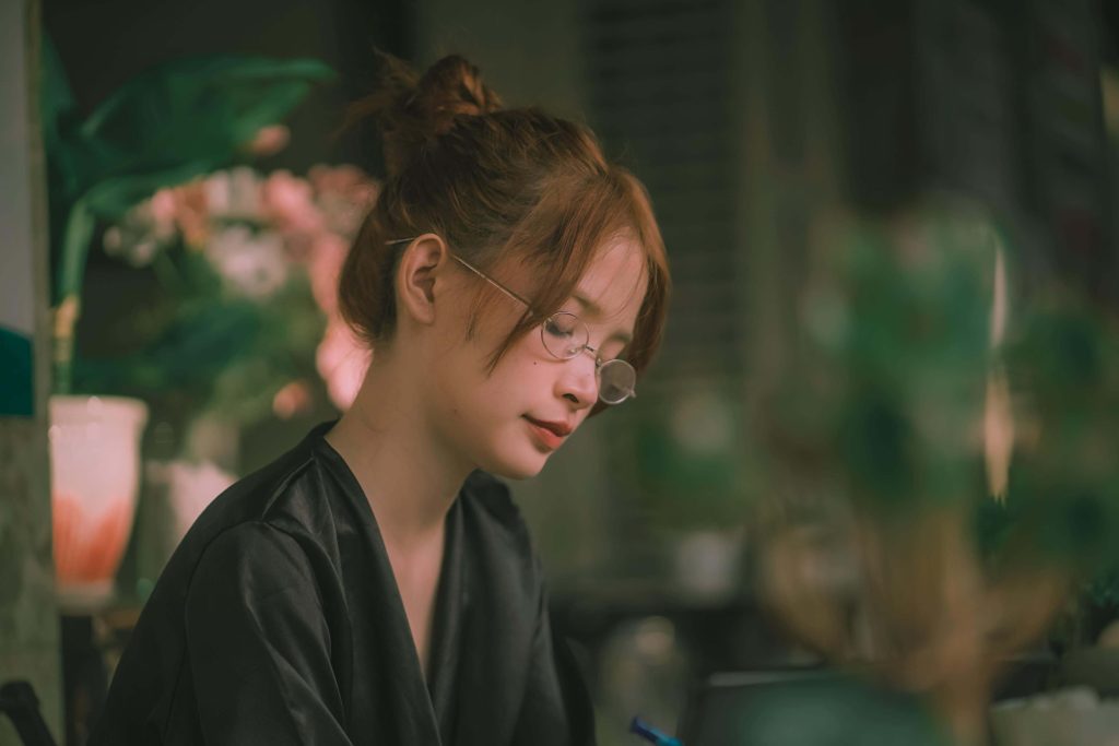Thoughtful woman sitting at a table writing. Extreme hunger can be difficult to overcome during recovery. With eating disorder recovery coaching in England you can begin to manage your symptoms.