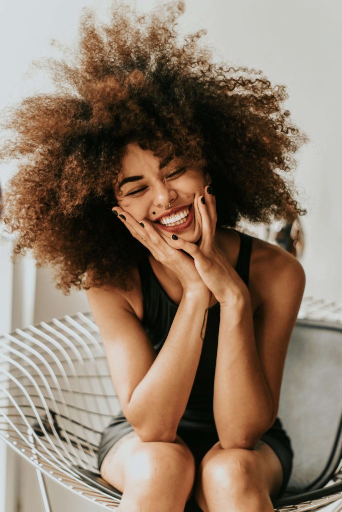 Happy woman touching her face and closing her eyes. Begin to find hope and start healing by overcoming your eating disorder challenges with eating disorder recovery coaching in England.