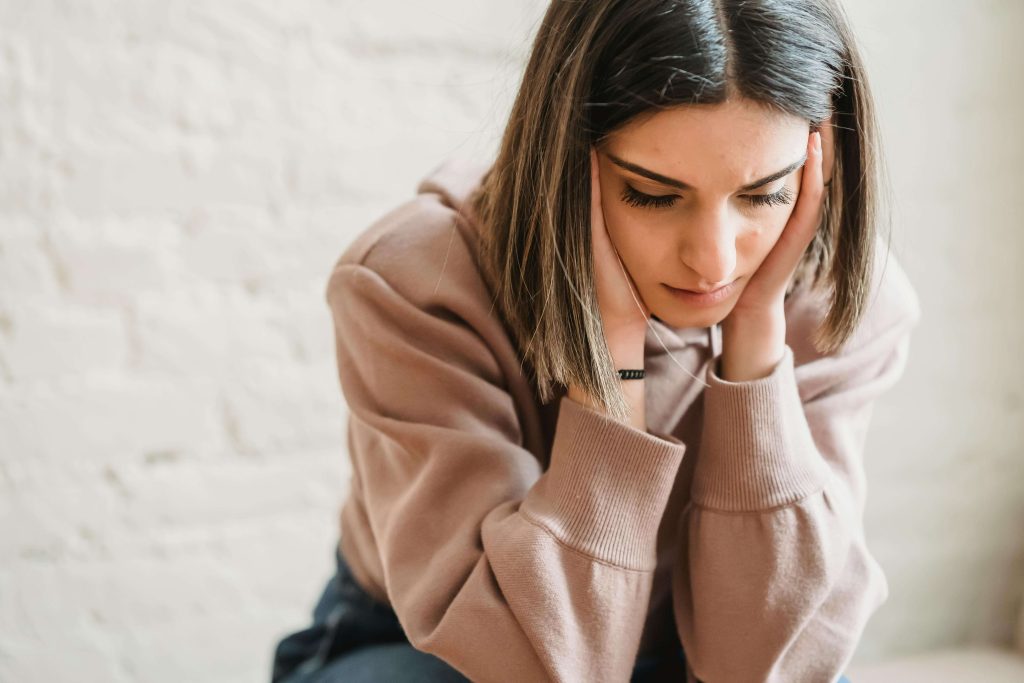 Upset woman resting her hands on the side of her face. Find compassionate support to heal and recover from your eating disorder with a British eating disorder recovery coach in England.