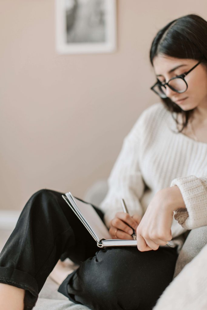 Young woman writing in a journal. Heal from your eating disorder and take back control of your life with the help of eating disorder recovery coaching in England.