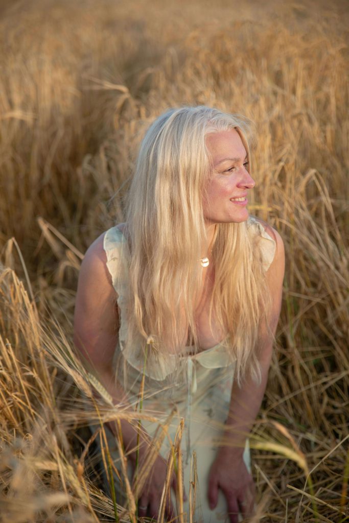 woman smiling in tall grass | eating disorder recovery coaching | British eating disorder recovery coach | anorexia recovery | Scotland | England | Ireland A woman sits in a field of tall grass, smiling peacefully, surrounded by warm sunlight and open space. Rediscover joy and hope with the guidance of a British eating disorder recovery coach—begin anorexia recovery through eating disorder recovery coaching in England.