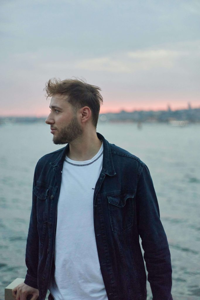 man by water | eating disorder recovery coaching in the uk | eating disorder recovery coach | ed recovery coach | England | Scotland | Ireland Man standing by the water at sunset, looking thoughtful. Rediscover your identity with the guidance of eating disorder recovery coaching in the UK.