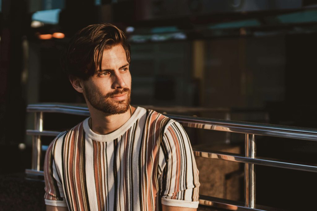 man sitting against rail | eating disorder recovery coaching | anorexia coach | eating disorder recovery coach | Ireland | England | Scotland A man in a striped t-shirt sits against a metal rail, reflecting in a quiet moment of stillness. With the support of eating disorder recovery coaching in England and guidance from an experienced anorexia coach, you can begin the process of healing and recovery.