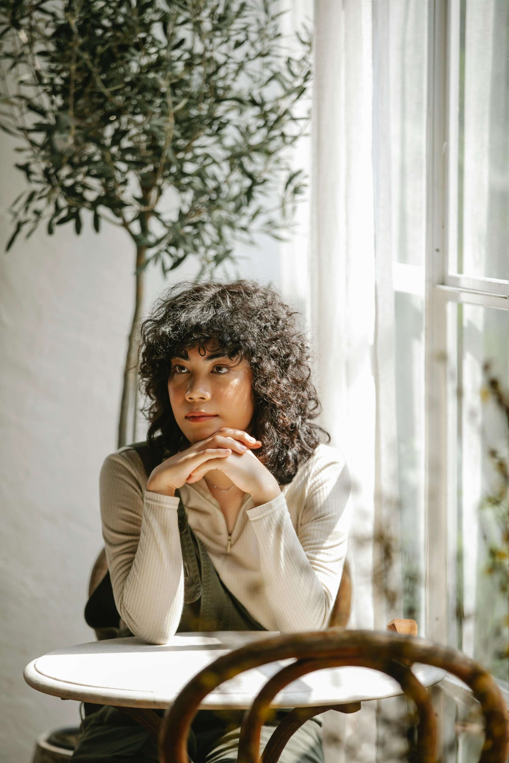 Thoughtful woman sitting at a cafe table. Begin to heal and start your recovery with the support of anorexia nervosa recovery in England.