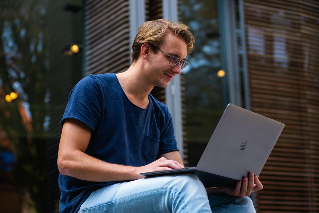 outdoor laptop | eating disorder recovery online in England | eating disorder coaching | british eating disorder recovery coach | England | Scotland | United Kingdom A man sitting outdoors using a laptop, smiling while participating in an online coaching session. Experience flexible, supportive eating disorder recovery online in England and reconnect with your well-being through personalised eating disorder coaching anywhere you are.
