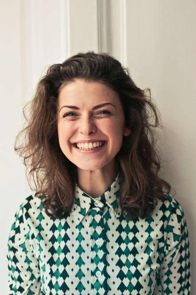 happy woman | eating disorder recovery coaching | anorexia recovery | british eating disorder recovery coach | England | Ireland | Scotland Happy woman wearing a green geometric shirt. Begin to reclaim your life from anorexia with the support of anorexia recovery coaching in England.
