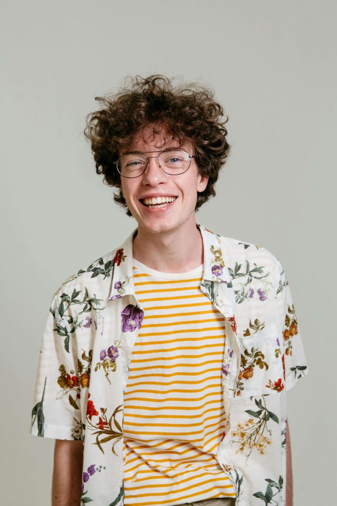 smiling person | eating disorder recovery online in England | eating disorder recovery coach | eating disorder recovery coaching | England | Wales | Ireland A smiling young man wearing glasses and a floral shirt, standing against a plain background and looking confident and relaxed. Build confidence and balance with eating disorder recovery online in England, supported by a compassionate eating disorder recovery coach who helps make recovery sustainable for everyone.