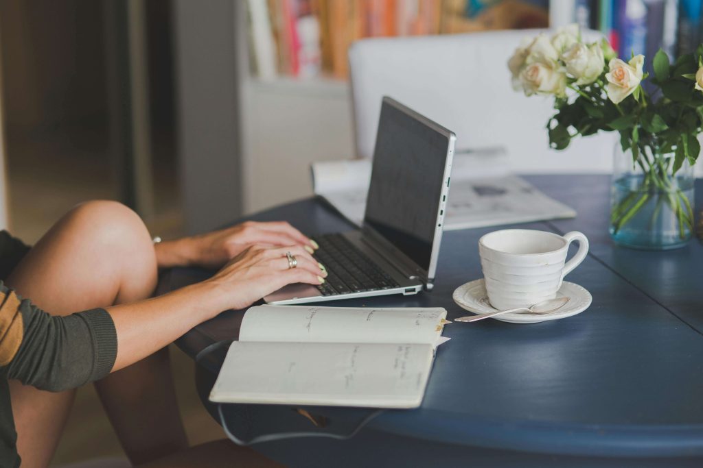 laptop | eating disorder recovery coaching | British eating disorder recovery coach | anorexia nervosa recovery | Scotland | Ireland | England Woman sitting at a table typing on a laptop. Work on your anorexia nervosa recovery and start your healing journey with eating disorder recovery coaching in England.