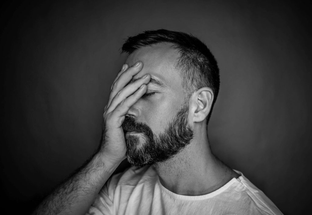 upset man | eating disorder recovery coaching in England | british eating disorder recovery coach | anorexia recovery coaching | England | Scotland | Ireland Black and white image of an upset man covering his face with his hands. Find help to avoid relapse or find support healing from an eating disorder with the help of eating disorder recovery coaching in England.